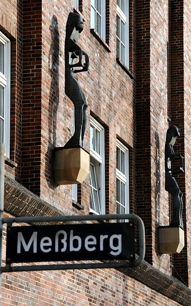 Strassenschild Meberg - Meberghof  33_48004 Strassenschild mit der Aufschrift MESSBERG vor der Hausfront des Meberghofs; die modernen Skulpturen sind von Lothar Fischer 1996-97 gefertigt worden. www.fotograf-hamburg.de