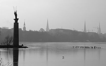011_14493 - grauer November in Hamburg; schemenhaft sind die Kirchtrme Hamburgs zu erkennen; die Alter ist mit dnnem Eis bedeckt; ein Schwarm Vgel sitzt auf dem Eis. 