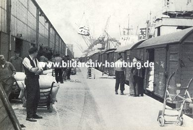 011_15567 historisches Bild - Hafenarbeiter beladen Gterzge mit Scken, die per Kran an Land gehievt werden und per Sackkarre auf der Landerampe transportiert werden. ( ca. 1930 )