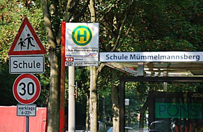 011_15994 - Bushaltestelle an der Schule Mmmel- mannsberg mit Schriftzug und Haltestellenschild. Warnschilder zeigen den Autofahrern, dass sie an der Schule rcksichtsvoll vorbei fahren mssen.