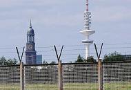 51_0099 Vom Wilhelmsburger Spreehafen kann das Panorama von Hamburg betrachtet werden. Blick durch den Zollzaun auf den Deich am Spreehafen - dahinter sind die beiden Hamburger Wahrzeichen die St. Michaeliskirche und der Heinrich Herzt Turm zu erkennen. Im Volksmund werden beide Trme auch "Michel" und "Telemichel" genannt. 