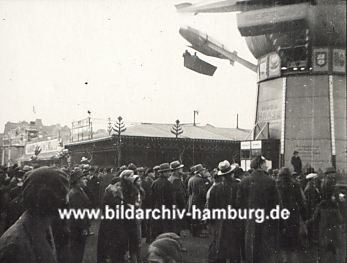 011_15229 - dicht gedrngt stehen die Menschen vor dem Karussell; ein Zeppelin trgt eine Gondel, in der die Fahrgste sitzen. (ca. 1930) 