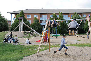 5040 Kinderspielplatz Neuallermhe - Jungendliche auf einer Schaukel -  Mtter spielen mit ihren Kindern im Sand.