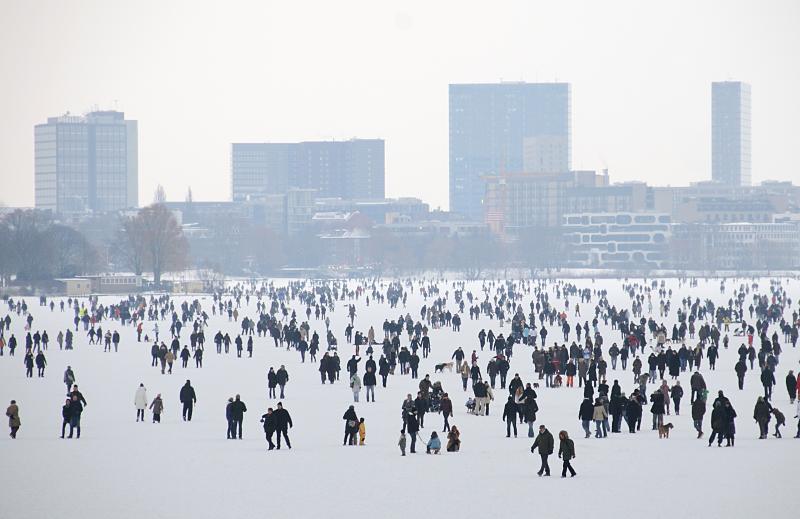 Hamburger Alster im frostigen Winter - Menschenmenge auf dem Eis. 250_6397 Blick ber die zugefrorene Auenalster Richtung Hochhuser in Hamburg St. Georg. Die Hamburger und Hamburger spazieren ber die Alster und genieen den Hamburger Winter. 