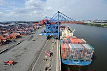 Blick auf den Ballinkai HHLA, Containerterminal Altenwerder - ein Containerfrachter liegt unter des Containerbr�cken des Terminals. Die Ladung des Frachters wird gel�scht. Der hochautomatisierte Containerumschlag auf dem HHLA Container Terminal Altenwerder ist in zwei Phasen aufgeteilt: An der Wasserseite l�schen und laden die besonderen, mit zwei Katzen ausgestatten Containerbr�cken die Stahlkisten vom bzw. auf das Schiff. Der Container wird auf einem h�her gelegenen Arbeitsportal abgesetzt, wo Lascher die Twistlocks entfernen bzw. anbringen. Au�erdem wird dort noch einmal die Kennung der Boxen �berpr�ft. Anschlie�end �bernimmt die zweite, so genannte Portalkatze den Container automatisch und setzt ihn auf ein Automated Guided Vehicle (AGV). 74 dieser Fahrzeuge sorgen f�r den Transport zwischen den Br�cken und dem Containerlager. Die AGV suchen sich den schnellsten Weg anhand von mehr als 10.000 Transpondern, die in den Boden eingelassen sind. Das Containerlager besteht aus 26 Lagerbl�cken, die von jeweils zwei RMG bearbeitet werden. Diese Lagerkr�ne sind unterschiedlich hoch und k�nnen daher parallel zueinander arbeiten