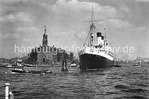 172_0276 Der Passagierdampfer Monte Rosa hat an den Holzdalben in der Elbe fest gemacht. Das Schiff lief 1930 vom Stapel und wurde auf der Hamburger Werft Blohm & Vo� gebaut. Eine Barkasse mit Hafenarbeitern f�hrt Richtung Baumwall und ein Binnenschiff biegt in Sandtorhafen ein, dessen Hafenbecken links im Hintergrund zu erkennen ist. Auf dem Uhrturm des 1876 erbauten Kaiserspeichers /  Kaispeichers ist die Zeitballanlage zu erkennen, die von der Sternwarte am Millerntor ausgel�st wurde. Der Ball hatte einen Durchmesser von einem Meter und wurde exakt Mittags um 12.00 Uhr weit sichtbar fallen gelassen.