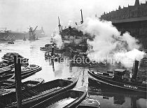 173_3502 Frachter liegen am Sandtorkai, Schute haben l�ngsseits fest gemacht - ein Schlepper unter Dampf kommt vom Brooktorhafen und f�hrt in den Sandtorhafen ein. Vor dem Kaiserkai wird ein Kohleheber von zwei Schleppern gezogen - im Hintergrund die Silhouette vom Kaiserspeicher und die M�ndung des Hafenbeckens in die Elbe.