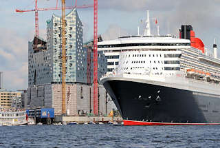 8552 Das Kreuzfahrtschiff Queen Mary luft aus dem Hamburger Hafen aus - im Hintergrund die Baustelle der Elbphilharmonie mit hohen Baukrnen. Ausflugsschiffe mit Touristen an Bord begleiten das Passagierschiff beim Auslaufen aus dem Hamburger Hafen.