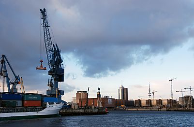 011_15372 - im Sdwesthafen entldt ein Kran ein Containerschiff / Feeder; im Hintergrund das Hamburg Panorama: lks. der Kaispeicher A, dahinter der Michel und rechts davon der Broturm vom HTC am Kehrwieder - rechts davon der Fernsehturm und die Baukrane der entstehenden Hafencity. 