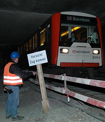 011_14323 - ein U-Bahnzug der Hamburger Hochbahn passiert eine Baustelle am Berliner Tor; ein Bahnarbeiter mit einem Signalhorn in der Hand steht am Schild " Vorsicht Zug kommt " und grsst den Fahrzeugfhrer.