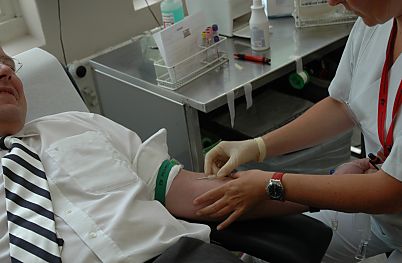011_14527 - der Blutspender liegt entspannt auf dem Stuhl; im Hintergrund die Blutproben + Karteikarte des Spenders.