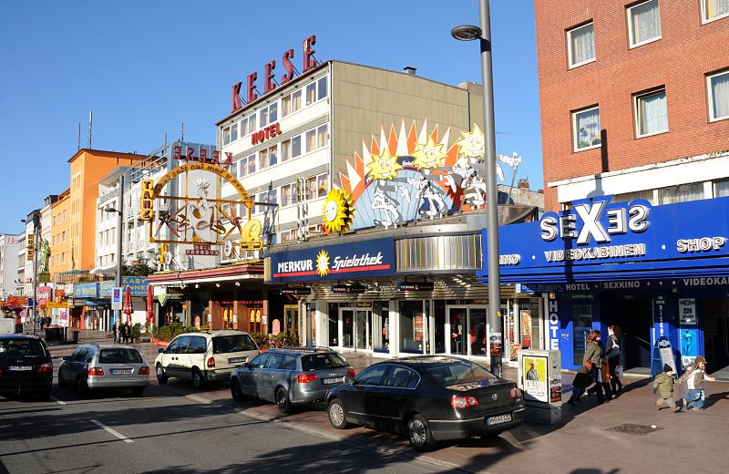 Bilder aus den Hamburger Bezirken // HH-Mittel, Stadtteil St. Pauli - Hamburgs Vergnuegungsviertel bei Tag - die Reeperbahn in der Sonne. Hamburger Fotograf Christoph U. Bellin. 34_41199 Die Reeperbahn in Hamburg - St. Pauli im Sonnenschein - Fussgnger gehen spazieren. Die Schilder an den Husern und Geschften weisen auf die unterschiedlichsten Aktivitten der Strae hin.  Die Reeperbahn ist die zentrale Strasse des Hamburger Vergngungsviertels auf St. Pauli. Hier finden sich neben Bars, Restaurants und Hotels auch Sexclubs und Theater. Die Reeperbahn hat ihren Namen Seilmachern / Reepschlgern, die ihr Handwerk ab 1633 in dem Bereich der jetzigen Reeperbahn ausgebt haben.