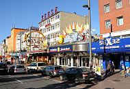 34_41199 Die Reeperbahn in Hamburg - St. Pauli bei Tag - Fugnger gehen im Sonnenschein spazieren. Die Schilder an den Husern und Geschften weisen auf die unterschiedlichsten Aktivitten der Strae hin.  Die Reeperbahn ist die zentrale Strasse des Hamburger Vergngungsviertels auf St. Pauli. Hier finden sich neben Bars, Restaurants und Hotels auch Sexclubs und Theater. Die Reeperbahn hat ihren Namen Seilmachern / Reepschlgern, die ihr Handwerk ab 1633 in dem Bereich der jetzigen Reeperbahn ausgebt haben.