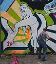 34_31213 Straßenreinigung auf Hamburgs sündiger Meile: die Reeperbahn im Hamburger Stadtteil St. Pauli. Eine aufreizende, nackte Frau ist als Graffiti an die Hauswand gesprüht,  ein Mann säubert darunter die Strasse mit einer Schaufel, im Vordergrund ein gefüllter Müllsack.