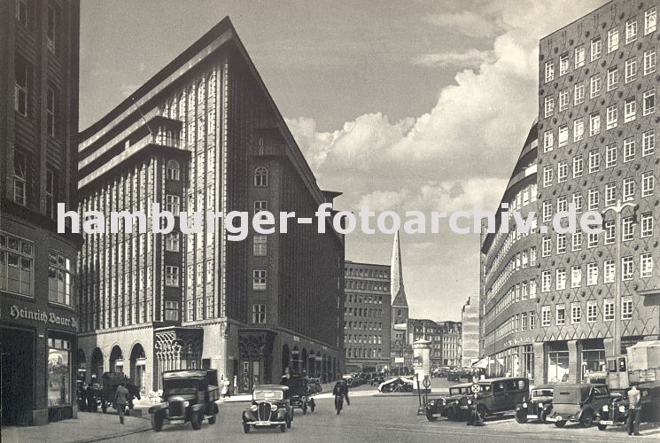 Fotos der Geschichte Hamburgs - historische Bildmotive  - Kontorhausviertel Chilehaus   33_47929 historisches Bild vom Hamburger Chilehaus ca. 1932. Autos stehen auf dem Parkplatz, ein LKW mit Plane hat am Strassenrand geparkt. Auf der linken Bildseite wartet ein beladenes Pferdefuhrwerk - in der Bildmitte ist die St. Petrikirche zu erkennen, davor eine Litfasule mit Werbung.  www.hamburg-fotos.biz