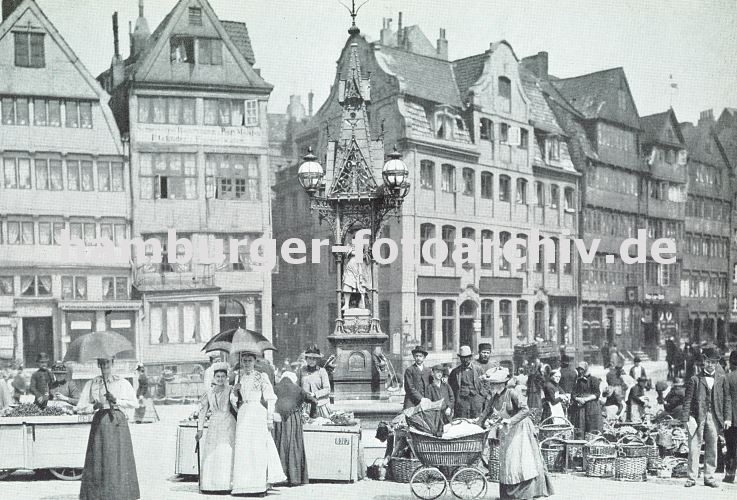 Bilder Hamburgs historische Architektur - Messberg und Fischerstwiete / Brunnen   33_47937 Marktgeschehen auf dem Messberg; Frauen mit Sonnenschirm und Kinderwagen, Buerinnen am Marktstand oder hinter Weidenkrben. In der Bildmitte der Vierlnder Brunnen, dahinter die Fischerswtiete und die historische Bebauung der Hamburger Altstadt, die nun u.a. zum Areal des jetzigen Chilehauses gehrt. www.hamburger-fotoarchiv.de