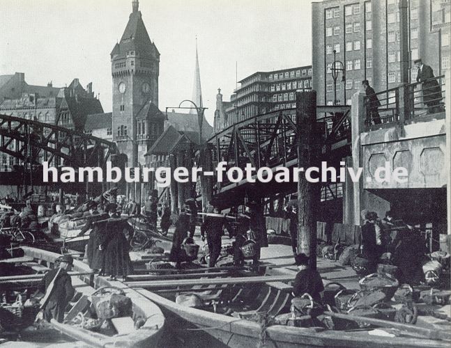 alte Fotos von Hamburg - historische Bilder vom Chilehaus / Zollkanal 33_47941 Bei der Wandrahmsbrcke haben Khne festgemacht, die Gemse fr den Markt am Deichtorplatz geladen haben. Buerinnen tragen mit Krben die Ernte an Land, um ihre Ware auf den Markt zu bringen. Hoch ragt der Uhrenturm der Wandrahmsbrcke am Kai des Messbergs empor. In der Bildmitte im Hintergrund ist das Chilehaus zu erkennen und rechts der Messberghof. www.hamburg-bilder.biz