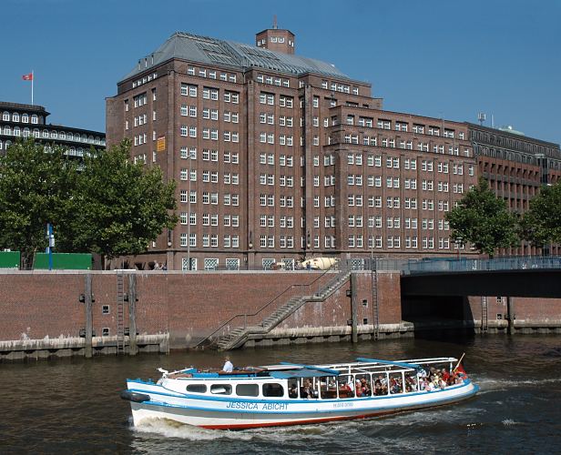 Hafenrundfahrt Hamburg - Bild Barkasse im Zollkanal, Wandrahmsteg  -- 33_47953 Eine Barkasse der Hamburger Hafenrundfahrt fhrt mit Touristen an Bord am Rande der Hamburger Speicherstadt auf dem Zollkanal; das Schiff hat gerade die Wand- rahmbrcke passiert. Seitenansicht der Backsteinarchitektur des Messberghofs, lks. ein Ausschnitt vom Chilehaus mit der Hamburg Fahne auf dem Dach. www.fotograf-hamburg.de