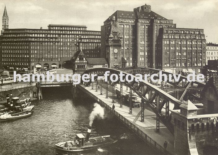 Fotos vom historischen Hamburg; Schlepper auf dem Zollkanal, Kontorhuser. -- 33_47953 Blick ber den Zollkanal ca. 1930 zum Messberg; Schlepper mit Kahn unter der Wandrahmbrcke n, ein Lastwagen mit Anhnger fhrt ber die Brcke in den Hamburger Freihafen. Rechts der Messberghof und lks. das Chilehaus. Dahinter ist die Turmspitze der St. Jacobikirche zu erkennen.  www.hamburg-fotos.biz