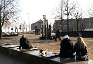 33_47992 Beim Messberg sitzen Hamburger in der Wintersonne auf dem mit Sitzbnken und einer Skulptur gestalteten Platz. Im Hintergrund Verkehr auf der ehemaligen Ost-West-Strasse und jetzigen Willy - Brandt - Strasse. Auf der anderen Seite der Hamburger Hauptverkehrsstrasse liegt der Wandrahmsteg und Gebude der Speicherstadt. www.fotograf-hamburg.de