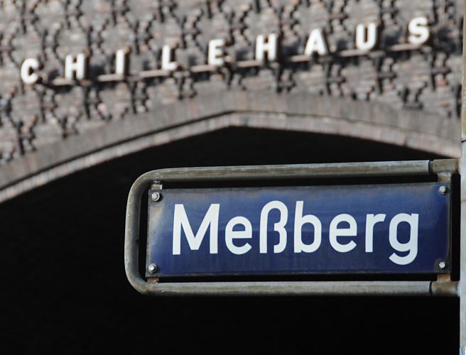 Foto vom Hamburger Strassenschild - Meberg und Chilehaus.  33_47998 Blaues Strassenschild mit weisser Schrift Meberg; im Hintergrund der Torbogen der Fischerstwiete, die durch das Kontorhaus fhrt. An der Hausfassade des Klinker-Kontorhauses ist der Schriftzug Chilehaus angebracht. www.fotograf-hamburg.de