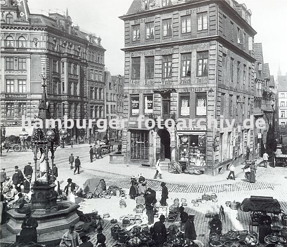 historische Bilder von Hamburg - Markt in der Hamburger Altstadt.  33_48005 lks. der Vierlnder Brunnen am Meberg. Die Brunnenanlage wurde 1878 errichtet; unter einem schmiedeeisernen Baldachin steht eine in ihrer Tracht gekleidete Vierlnderin aus Sandstein. Sie wurde von dem Bildhauer Engelbert Pfeiffer geschaffen, der z.B. auch das Bugenhagen Denkmal am Hamburger Johanneum gefertigt hat. In dem Geschft Ecke Klingenberg befindet sich ein Handel mit Eisenwaren - es werden dort Schiffszubehr, Ankerketten, Drahtseiel und Werkzeuge angeboten; im Souterrain befindet sich ein Geschft mit Farben und Drogen. www.hamburg-bilder.biz