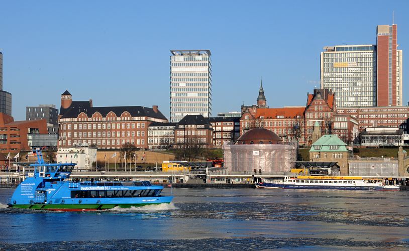 Fotos der Hamburger Sehenswrdigkeiten - Panorama der Landungsbrcken / Alter Elbtunnel  33_48037 Das kupfergedeckte Kuppelgebude vom Eingang des Alten Elbtunnels wird noch restauriert und ist teilweise mit Planen geschtzt. Der St. Pauli Elbtunnel wurde 1911 erffnet und gilt als Meisterleistung der Ingenieurskunst; ca. 4400 Arbeitskrfte arbeiteten fast vier Jahre an den beiden 426m langen Tunnelrhren. Auf zwei Fahrbahnen knnen Fussgnger und PKW die Elbe in 24m Tiefe unterqueren - Fahrsthle transportieren die Autos und Menschen hinunter. Hinter der Kuppel des Elbtunnels liegt das historische Gebude der Navigationsschule und auf der linken Seite die Schumacher-Architektur vom Tropeninstitut. www.bilder-hamburg.de