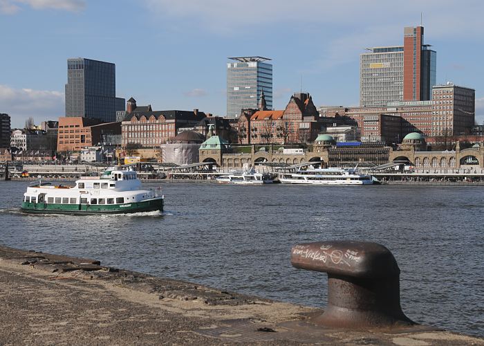 Hamburger Fotografien - Bilder;  Fotos der Hansestadt Hamburg, Hafen / Elbtunnel  33_48041 Hamburger Hafen - Panorama; Eingangsgebude des Alten Elbtunnel und Teile der St. Pauli Landungsbrcken; Hochhuser bestimmen die Silhouette am Elbufer - dazwischen sind die historischen Gebude vom Hamburger Tropeninstitut und der Navigationsschule. In der Bildmitte das kupfergedeckte Kuppelgebude vom Eingang des Alten Elbtunnels, der restauriert wird. Eine historische Hafenfhre wird als Schiff der Hafenrundfahrt fr Hamburg-Touristen genutzt. Im Vordergrund ein alter Poller an der ehemaligen Kaianlage - sie gehrte zur Werft, die sich gegenber der St. Pauli Landungsbrcken befand.  www.fotos-hamburg.de