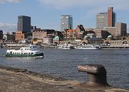 33_48041 Hamburger Hafen - Panorama; Eingangsgebude des Alten Elbtunnel und Teile der St. Pauli Landungsbrcken; Hochhuser bestimmen die Silhouette am Elbufer - dazwischen sind die historischen Gebude vom Hamburger Tropeninstitut und der Navigationsschule. In der Bildmitte das kupfergedeckte Kuppelgebude vom Eingang des Alten Elbtunnels, der restauriert wird. Eine historische Hafenfhre wird als Schiff der Hafenrundfahrt fr Hamburg-Touristen genutzt. Im Vordergrund ein alter Poller an der ehemaligen Kaianlage - sie gehrte zur Werft, die sich gegenber der St. Pauli Landungsbrcken befand. www.fotos-hamburg.de