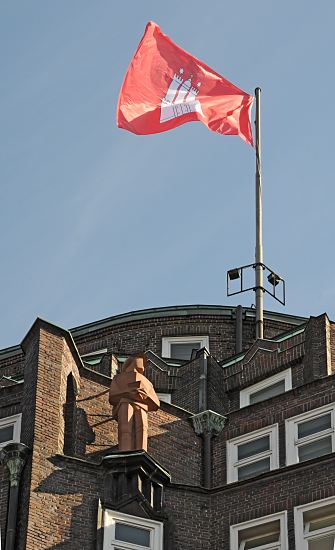 Bild der Hamburg Flagge, Hausdach    33_48050 Die Hamburgflagge weht auf dem Gebudedach des Montanhofs; das expressionistische Klinkergebude der Architekten Distel + Grubitz ist mit Skulpturen an der Hausfassade dekoriert. www.fotograf- hamburg.de