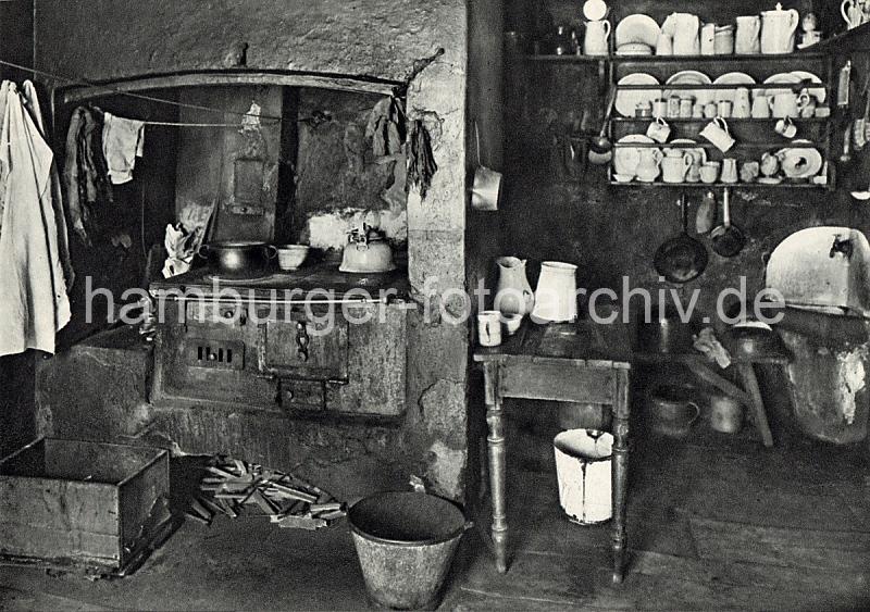 Historische Hamburg-Motive - Wohnen im Hamburger Gngeviertel. Kche mit Holzofen und Feuerholz - Handwaschbecken, Porzellan im Regal.  06_076_2 Als Gngeviertel wurden die besonders eng bebauten Wohnquartiere in einigen Teilen der Hamburger Altstadt und Neustadtbezeichnet. Die Gngeviertel waren grtenteils mit Fachwerkhusern bebaut, deren Wohnungen zumeist nur durch schmale Straen und ber Hinterhfe und den Gngen zwischen den Husern zu erreichen waren.  In den Gngevierteln wohnten meist mittlere und rmere Bevlkerungsschichten; aufgrund der schlechten hygienischen Zustnde, aber auch aus sozialen und politischen Bestrebungen begannen bereits zum Ende des 19. Jahrhunderts die ersten Sanierungsmanahmen durch Abriss.