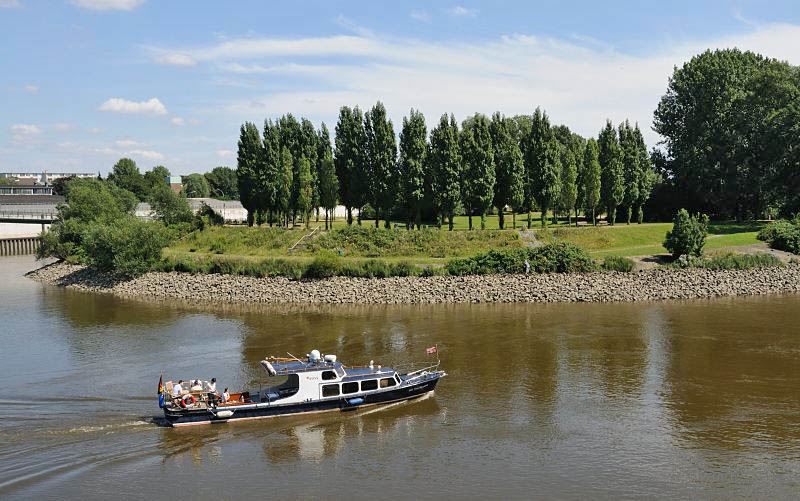 Fotos aus dem  Hamburger Stadtteil Rothenburgsort - Motorboot auf der Norderelbe vor dem Elbpark Entenwerder.  1455_3913 Ein Sportboot kommt aus der Richtung Billehafen und fhrt am Elbpark Entenwerder vorbei in die Norderelbe. Die Passagiere des Motorboots sitzen am Heck des Schiffs in der Sonne.