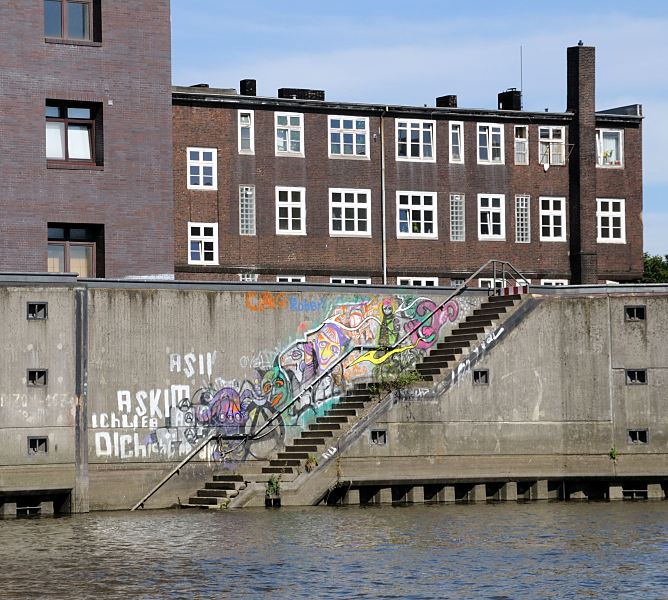 Bilder aus den Hamburger Stadtteil Rothenburgsort Hamburg - Mitte. Wassertreppe im Billhafen - Graffiti.  1466_3980 Im Billhafen fhrt eine Treppe hinunter zum Wasser des Hafenbeckens - die Wand ist mit buntem Graffiti bedeckt. Hinter der Kaimauer die dunkelroten Klinker eines der historische Gebude am Billehafen.
