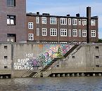 1466_3980 Im Billhafen führt eine Treppe hinunter zum Wasser des Hafenbeckens - die Wand ist mit buntem Graffiti bedeckt. Hinter der Kaimauer die dunkelroten Klinker eines der historische Gebäude am Billehafen. 