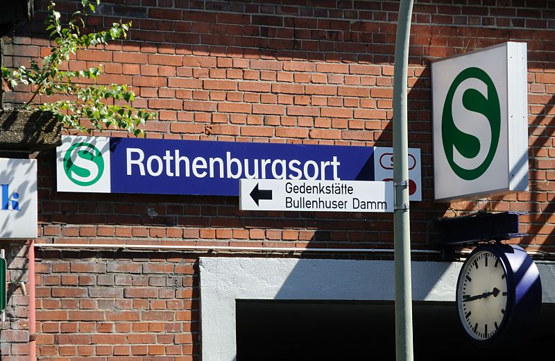 Hamburg-Bilder aus dem Bezirk HH-Mitte, Stadtteil Rothenburgsort. S-Bahnstation Rothenburgsort - Wegweiser Gedenksttte Bullenhuser Damm. 474_ 3963 Schild S-Bahn Bahnhof Hamburg Rothenburgsort ber dem Eingang - eine Bahnhofsuhr zeigt die Zeit an. Aus dem Mauerwerk des Bahnhofgebudes wchst ein junge Birke - ein Hinweisschild zeigt die Richtung zur Gedenksttte Bullenhuser Damm.474_ 3963 Schild S-Bahn Bahnhof Hamburg Rothenburgsort ber dem Eingang - eine Bahnhofsuhr zeigt die Zeit an. Aus dem Mauerwerk des Bahnhofgebudes wchst ein junge Birke - ein Hinweisschild zeigt die Richtung zur Gedenksttte Bullenhuser Damm.