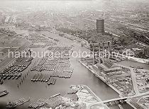 1485_0569  Luftansicht der Billwerder Bucht - dicht ankern die Binnenschiffe vor Hamburg Rothenburgsort. Im Vorder- grund rechts die Mndung vom Moorfleeter Kanal und die vier Schornsteine des Kraftwerks Tiefstack, die in das Logo der Hamburgischen Electricitts Werke HEW aufgenommen wurden. Hinter dem Kraftwerksgebude die Schleuse zum Tiefstack-Kanal und die Anlage des Gaswerks Rothenburgsort. Dahinter die Gleisanlagen des Rangierbahnhofs von Rothenburgsort. Links auf der Elbinsel Kaltehofe sind die Filterbecken der Wasserwerke zu erkennen.