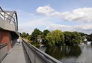 1489_4479  Eine Fussgngerbrcke fhrt neben der Eisenbahnbrcke ber den Bullenhuser Kanall - zwei Fussgngerinnen berqueren die Brcke.  Am Ufer des Kanals wachsen auf dem Kleingartengelnde Weiden - Sportboote liegen an den Stegen der Grundstcke.