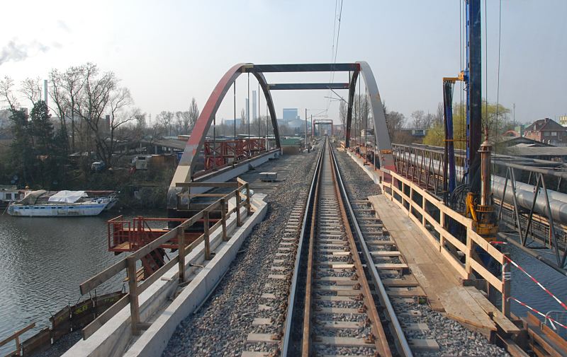 Hamburg-Bilder aus den Bezirken; Bezirk Hamburg Mitte, Stadtteil Rothenburgsort Ertchtigung der Gterzugstrecke - Bau von Lrmschutzwnden; 03/2007.  1490_1_0491  Im Rahmen der sogen. Ertchtigung der Gterumgehungsbahn durch Hamburg wurde die Strecke fr den steigenden Gterzugverkehr baulich vorbereitet. Das Aufkommen an Gterzgen sollte von ca. 35 Zge in 24 Std. auf ca. 84 Zge ansteigen, die eine Lnge bis zu 600m haben knnen. Auch wurde durch die bauliche Instandsetzung der Strecke die Geschwindigkeit der Gterzge von ca. 60 km/h auf 80 km/h gesteigert. Um den dadurch entstandenen hheren Lrmpegel zu reduzieren, wurden in Wohngegenden Lrmschutzwnde entlang der Gterzugstrecke gebaut. Blick auf die Eisenbahnbrcke ber den Bullenhuser Kanal nach Hamburg Rothenburgsort. 03/2007.