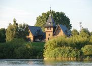 1509_3774  In der Villa mit dem spitzen Turmdach hinter dem Deich der Norderelbe war das Labor und Teile der Verwaltung der Wasser-Filtrierwerke von Kaltehofe untergebracht. Weiden und hohes Schilf stehen am Ufer der Elbe.