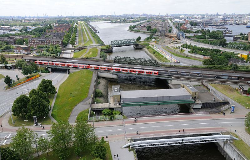 Luftbild von der Veddel - Blick zum Spreehafen und dem Hansahafen. 214_0043 Im Vordergrund hinter der Wilhelmsburger Brcke das Mggenburger Sperrwerk und die S-Bahnstation Veddel - ein roter S-Bahnzug steht an der Haltestelle. Die Backstein- Wohhuser auf der linken Bildseite gehren noch zum Stadtteil Veddel, dahinter beginnt Hamburg-Wilhelmsburg. Der Spreehafen im Bildzentrum und der Hansahafen lks. sind Teil des Stadtteils Kleiner Grasbrook.