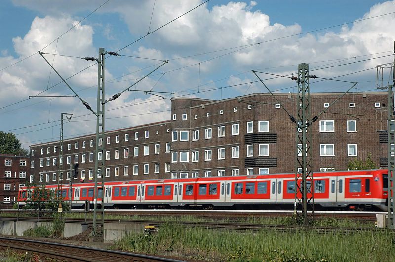 Hamburgbilder aus dem Bezirk Mitte; Stadtteil Veddel S-Bahn-Zug auf den Bahngleisen Veddel, Wohngebude - Hamburgfotos Christoph Bellin. 224_0432 Auf den Gleisen Eisenbahnstrecke am Rand der Veddel fhrt ein roter S-Bahnzug zum Hamburger Hauptbahnhof. Nahe der Bahnstrecke liegen die Wohngebude an der Strasse "Am Gleise".