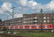 224_0432 Auf den Gleisen Eisenbahnstrecke am Rand der Veddel fährt ein roter S-Bahnzug zum Hamburger Hauptbahnhof. Nahe der Bahnstrecke liegen die Wohngebäude an der Strasse "Am Gleise".