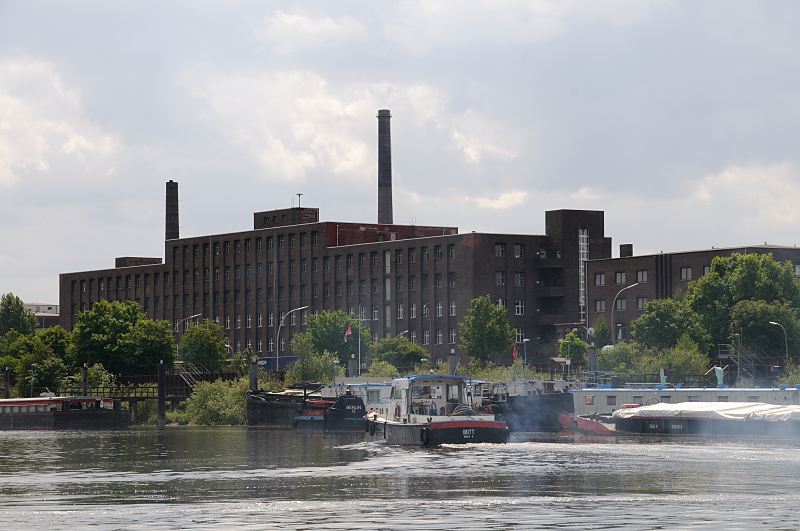 Hamburg-Fotografien aus dem Bezirk Hamburg-Mitte, Stadtteil Veddel. Barkasse im Peute Hafen - Industriearchitektur, Backstein Fabrikgebude. Fotografie aus Hamburg - Christoph Bellin. 230_8304 Eine Barkasse fhrt im Peutehafen zu ihrem Liegeplatz - weitere Arbeitsboote und Binnenschiffe haben in dem Veddeler Hafenbecken fest gemacht. An Land die beeindruckende historische Industriearchitektur der 1920er Jahre - in dem Fabrikgebude hatte die Groeinkaufs-Gesellschaft Deutscher Consumvereine mbH GEG ihren Sitz.