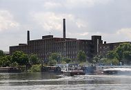 230_8304 Eine Barkasse fhrt im Peutehafen zu ihrem Liegeplatz - weitere Arbeitsboote und Binnenschiffe haben in dem Veddeler Hafenbecken fest gemacht. An Land die beeindruckende historische Industriearchitektur der 1920er Jahre - in dem Fabrikgebude hatte die Groeinkaufs-Gesellschaft Deutscher Consumvereine mbH GEG ihren Sitz.