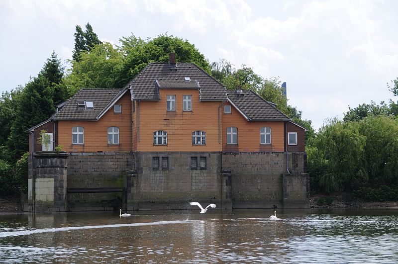 Bilder aus den Hamburger Bezirken - Bezirk Hamburg Mitte, Peute / Veddel ehem. Schleusengebude der Mggenburger Schleuse. Fotograf Christoph Bellin, Hamburg. 236_8446 Schleusengebude der Mggenburger Schleuse; die Schleuse, die am Ende des Mggenburger Kanals und des Hovekanals lag, verband die Veddeler Wasserwege mit der Norderelbe. Schwne schwimmen auf dem Kanalgewsser, einer der grossen Schwimmvgel hebt gerade ab.