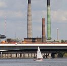 241_1092 Hinter der Autobahnbrcke der Bundesautobahn 255 / Abzweig Veddel die hohen Schornsteine der Kupferhtte Aurubis als Wahrzeichen des Industriegebietes auf der Peute. Ein Segelboot fhrt auf dem Wasser des Mggenburger Zollhafens - die Optimistenjolle wird von Schlern und Schlerinnen der Veddeler Schule Slomanstieg genutzt.