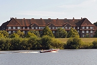 242_4049 Auf dem Spreehafen, der schon zum Hamburger Stadtteil Kleiner Grasbrook gehrt, fhrt ein Sportboot. Hinter dem Kltjenfelder Hauptdeich Backstein-Wohnblocks an der Harburger Chaussee. Am Deich verluft die Zollgrenze, ein hoher Zaun sperrt das Gebiet gegen Schmuggler und Fugnger ab.