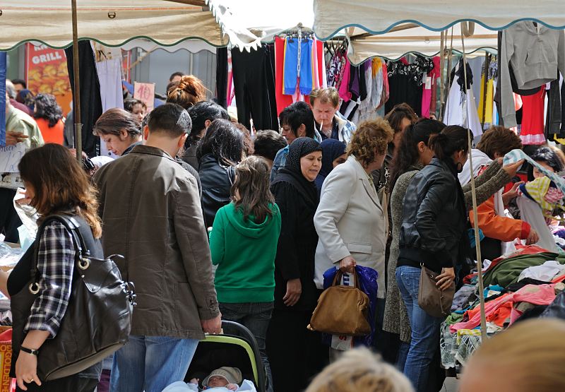 Wochenmarkt auf dem Wilhelmsburger Stbenplatz - Marktstnde Bilder aus dem Hamburger Bezirk Mitte; Stadtteil Wilhelmsburg  100_4_9861 Auf dem Wilhelmsburger Wochenmarkt knnen die Besucher neben  Gemse und Obst auch vielerlei Kleidung kaufen. Zwischen den Marktstnden herrscht dichtes Gedrnge - die Marktbesucher und Marktbesucherinnen mustern die auf Tischen ausgelegten Kleidungsstcke.