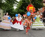 100_8_9942 Farbenprächtiger Umzug Fest der Kulturen - Tänzerinnen und Tänzer ziehen durch Wilhelmsburg. Der Kopfschmuck des Tänzers ist mit roten und gelben Federn geschmückt - die Tänzerinnen tragen bunte weite Kleider - sie haben ebenso wie die Zuschauer Freude ihrem Auftritt.