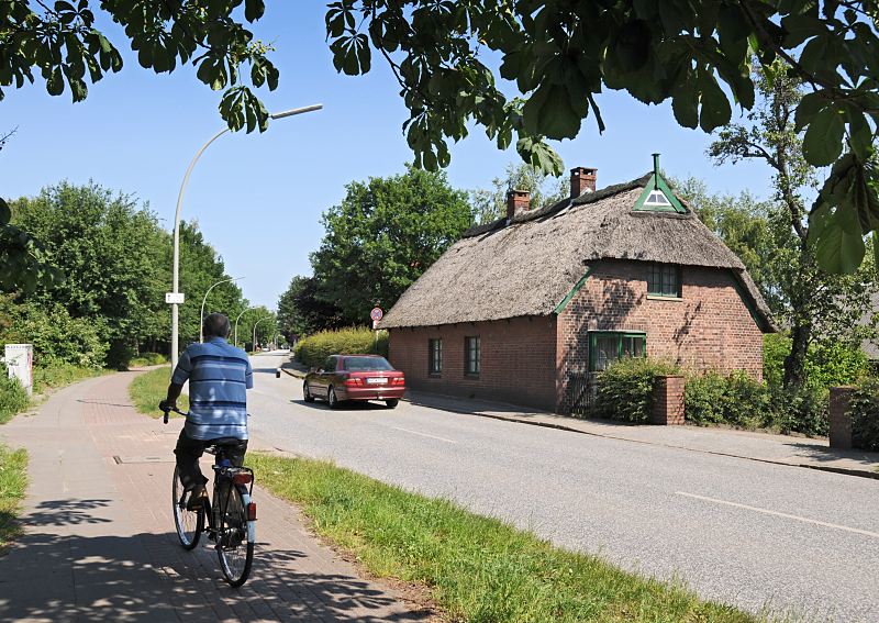 Motive aus dem Hamburger Bezirk Mitte; Wilhelmsburg, Georgswerder 108_8913 Georgswerder ist ein Ortsteil des Stadtteils Wilhelmsburg. Ein historisches Strohdachhaus steht dicht an der Georgswerder Strasse Niedergeorgswerder Deich. Die Bltter eines Kastanienbaumes spenden Schatten, ein Fahrradfahrer fhrt auf dem Radweg.  www.bilder-hamburg.de